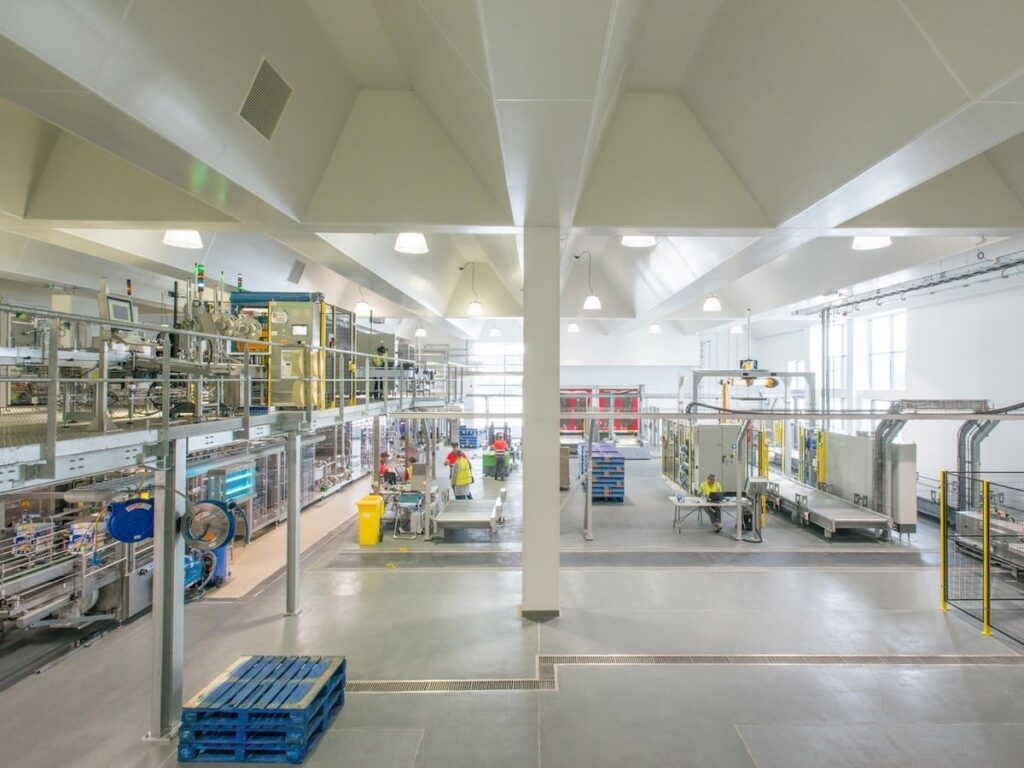 Food and beverage processing facility with hygienic wall cladding, white PVC hygienic wall panels, and stainless steel production equipment